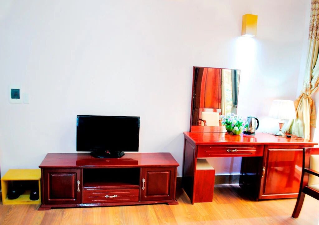 Un mueble de televisión de madera con un televisor de pantalla plana, un escritorio con un espejo y una lámpara.