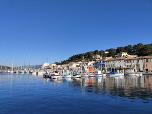 A marina with boats docked, a clear blue sky, and buildings along the water's edge.