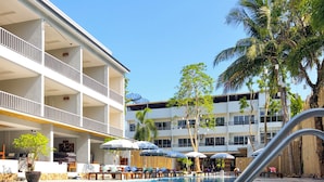 Una piscina con superficie de agua azul cristalina, rodeada por un edificio con múltiples balcones y zonas de estar al aire libre.