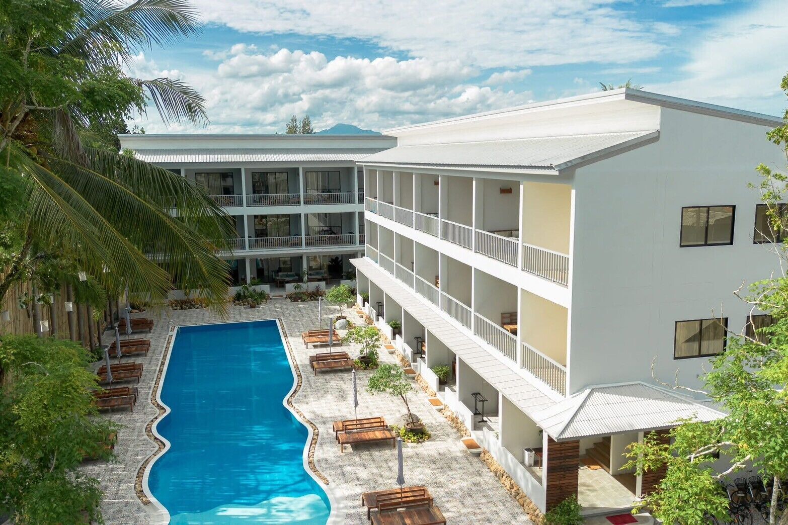 A hotel with a swimming pool, outdoor seating, and a multi-story building.