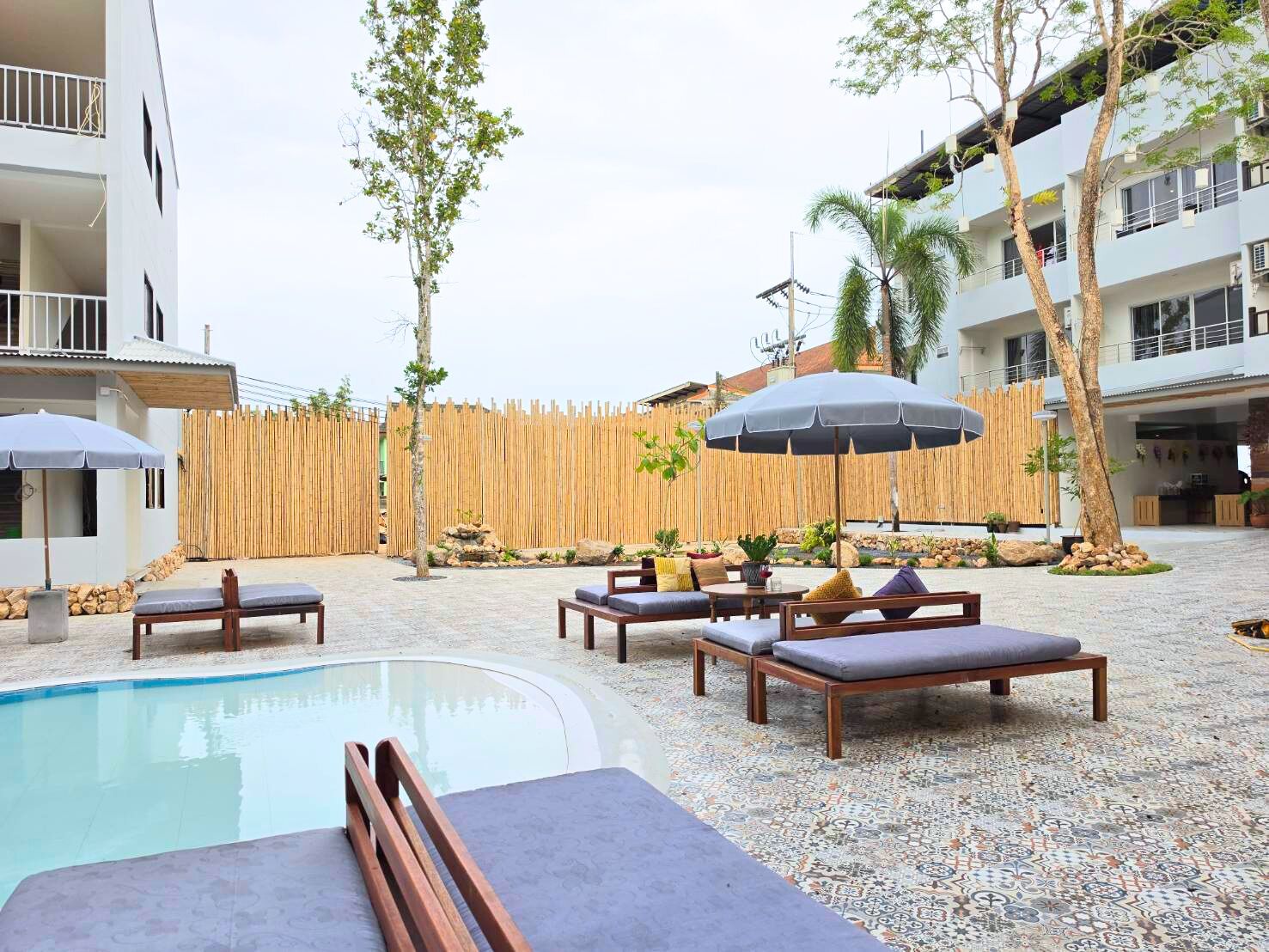 A pool area with lounge chairs, umbrellas, and a wooden fence.