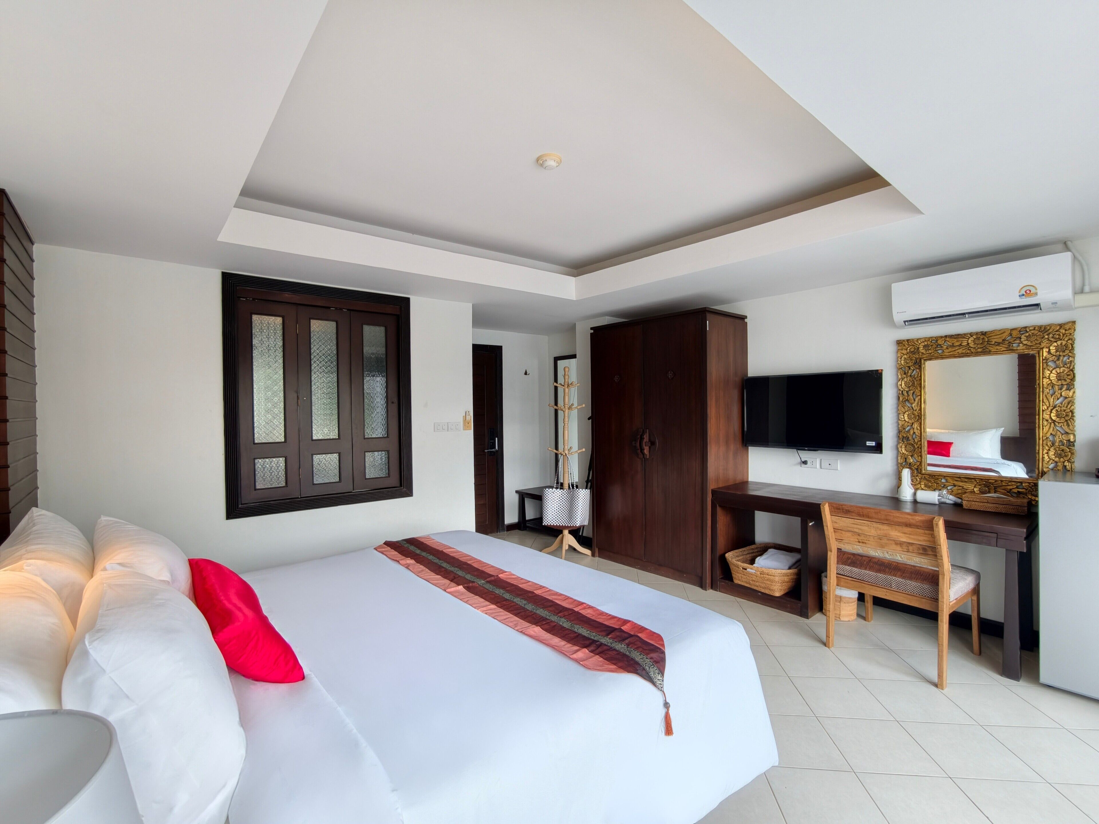 Una habitación de hotel con cama, escritorio, televisor y armario.
