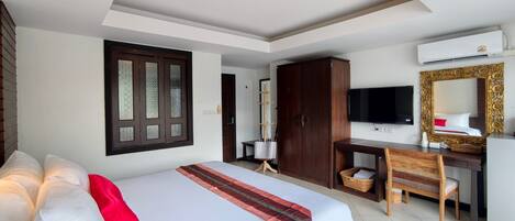 Una habitación de hotel con cama, escritorio, televisor y armario.