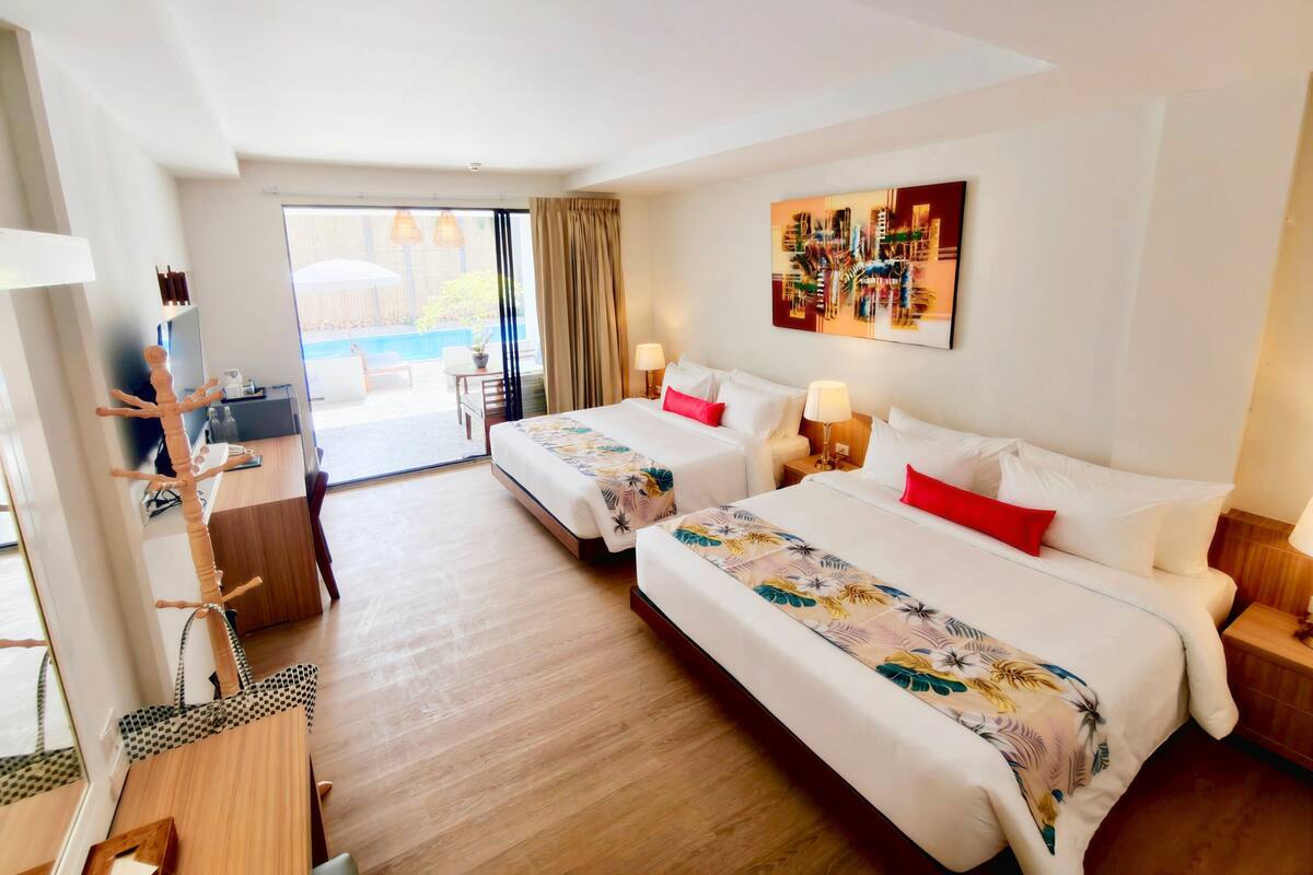 Een hotelkamer met twee bedden, een bureau, een stoel, een televisie en een balkon met uitzicht.