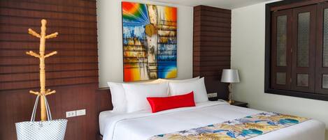 Habitación de hotel con cama, perchero de madera, un cuadro de colores, lámpara y ventana con vistas.