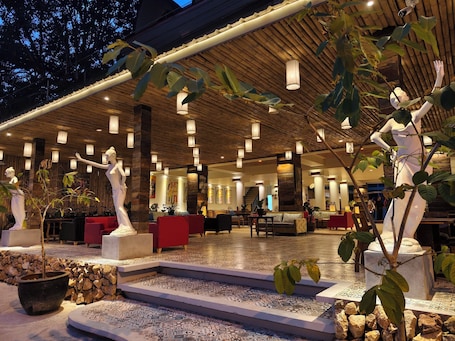 A spacious lobby with a wooden ceiling, multiple seating areas, and decorative statues.