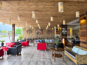 Um hall amplo com teto de madeira, várias áreas de estar e vista para o exterior.