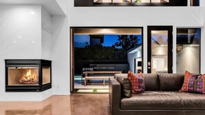 A modern living room with a fireplace, a leather sofa, and a view of the outdoors.
