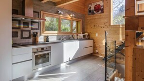 A modern kitchen with a large window, stainless steel appliances, and wooden accents.