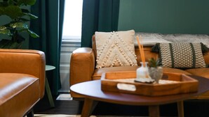 Een gezellige woonkamer met een bruine leren bank, een ronde houten salontafel en een potplant.