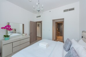 Une chambre à coucher moderne avec un grand lit, une commode, un miroir et un lustre.