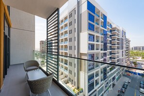 Un immeuble d’appartements moderne doté de balcons, d’une rambarde en verre et offrant une vue sur les environs.