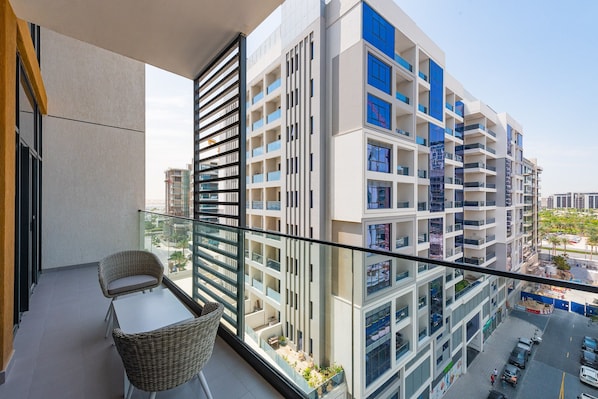 A modern apartment building with balconies, a glass railing, and a view of the surrounding area.