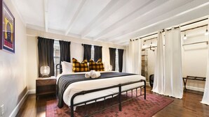 Ein Schlafzimmer mit Bett, Nachttisch, Fenster mit Vorhängen und einer Duschkabine.