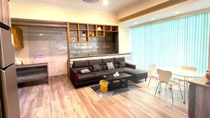 Een moderne woonkamer met een bank, salontafel en eethoek.