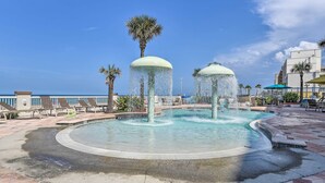 A circular pool with water jets, surrounded by lounge chairs and palm trees. - Daytona Beach Studio Condo w/ Ocean Views! (Daytona Beach)