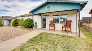 A residential building with a covered patio, two wooden chairs, and a small lawn. - New Mexico Smart Home w/ Private Yard & Grill (Tucumcari)