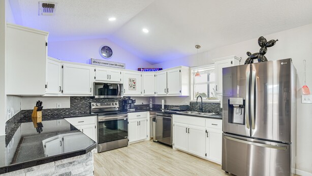 A modern kitchen with white cabinets, stainless steel appliances, and a black countertop. - New Mexico Smart Home w/ Private Yard & Grill (Tucumcari)