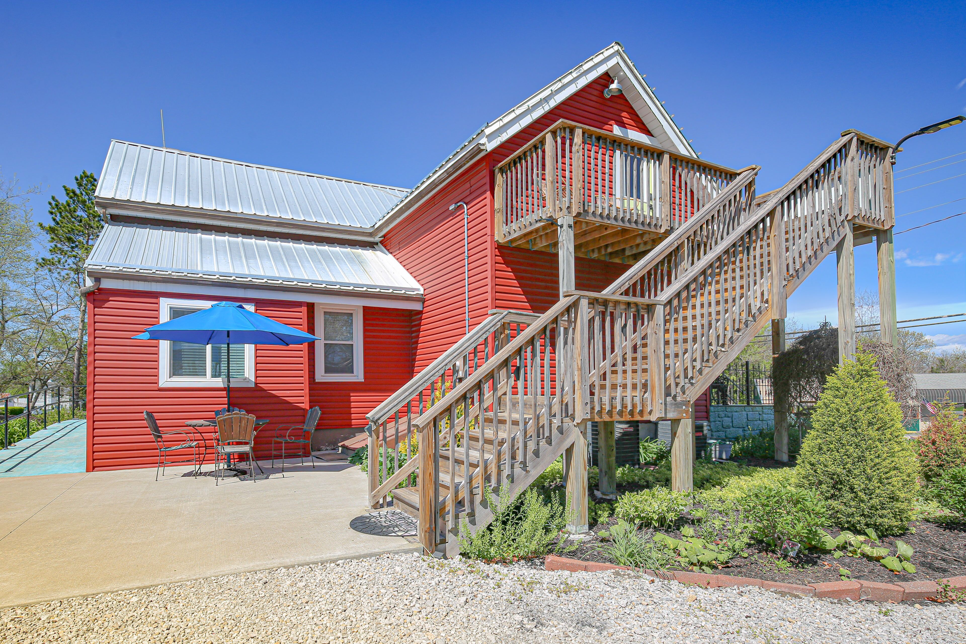 A red building with a wooden staircase and a blue umbrella.