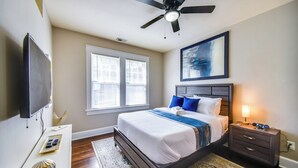 Een slaapkamer met een bed, nachtkastje en een plafondventilator.