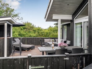 An outdoor deck with seating, a table, and a view of greenery.