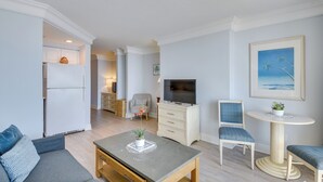 Een moderne woonkamer met een bank, salontafel, televisie en een eethoek met tafel en stoelen.