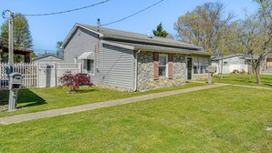 A single-story house with a stone foundation and a gabled roof, surrounded by a small lawn and a wooden fence. - Harrisburg Home w/ Private Yard + Screened Porch! (Harrisburg)