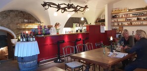 L’intérieur d’un restaurant, avec un bar, des tables et des chaises en bois, et un présentoir à bouteilles de vin.