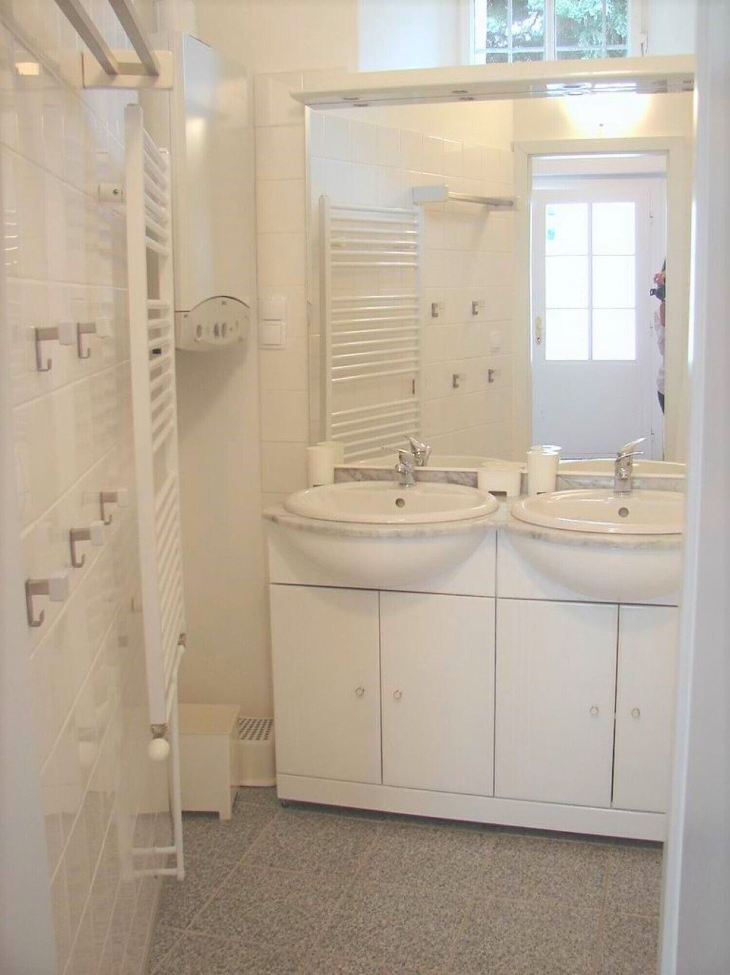 Un baño con dos lavamanos, un espejo y un perchero para toallas.