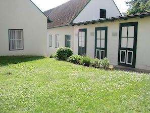 A building with a white exterior, green window frames, and a sloped roof.