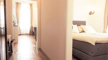 A hallway leading to a bedroom with a bed, a dining area, and a view of the outside.