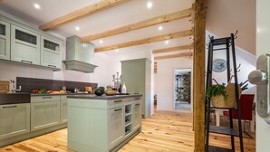 Een moderne keuken met houten balken, lichtgroene kastjes en een centraal kookeiland.