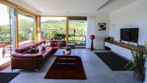 Uma sala de estar moderna com uma janela grande, um sofá, uma mesa de centro e uma televisão.