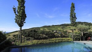 Piscina com vista para colinas ondulantes e céu claro.