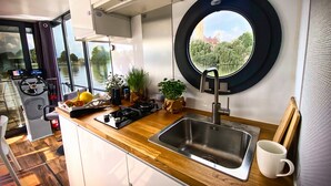 A compact kitchen with a window, a sink, and a stove. - Boat 'Cosy Hannah Führerscheinfrei' with Private Terrace (Schwerin)