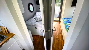 A compact room with a bed, a small window, and a door leading to another room. - Boat 'Cosy Hannah Führerscheinfrei' with Private Terrace (Schwerin)