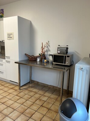 Eine Küchenzeile mit einer Mikrowelle, einem kleinen Kühlschrank und einem Mülleimer.