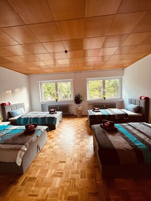Una habitación con dos camas, un radiador y una ventana con vistas a árboles.