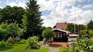 A house with a red roof, a garden with various plants, a stone pathway, and a small shed. - Apartment 'Ferienhaus Gerda Wohnung 2' with Private Terrace, Private Garden and Wi-Fi (Ochtersum)