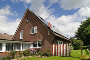 Et tofarget murhus med skrå tag, parabolantenne og en indhegnet have.