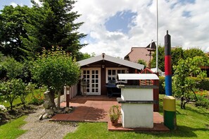 Et hus med terrasse, have og et højt stang.