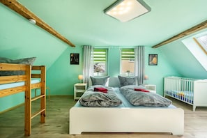 Una habitación con literas, una cama individual, una cuna y un tragaluz.