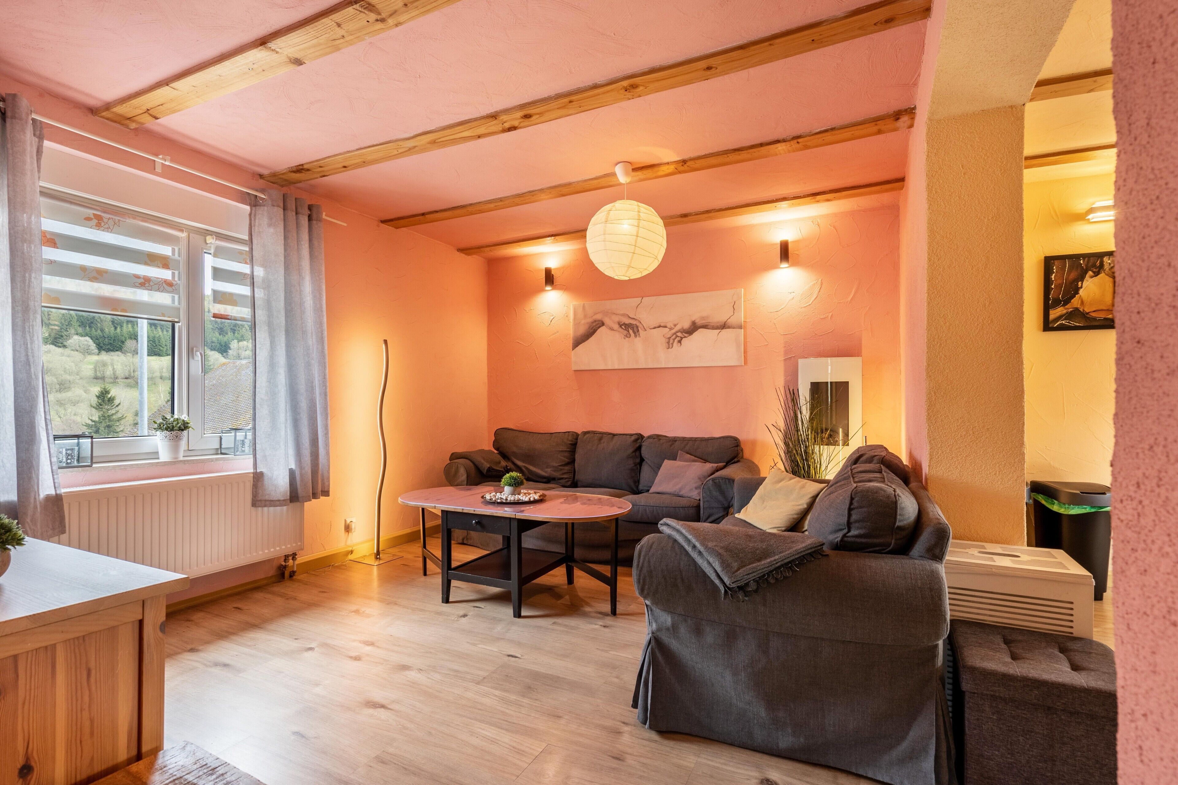 A cozy living room with a sofa, a coffee table, a radiator, and a window with curtains.