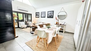A modern dining area with a round table, white chairs, and a large mirror on the wall. - Luxury Apartment St Lucia 43 On the Bridge (Saint Lucia)