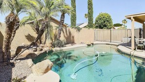 A swimming pool with palm trees and a fence in the background.