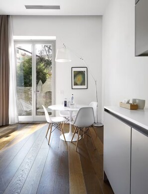 A modern kitchen with white cabinets, a white countertop, and a dining area with a round table and chairs.
