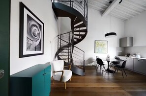 A modern kitchen with a spiral staircase, a dining area with chairs, and a teal cabinet.