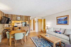 A modern living room with a sofa, coffee table, and dining area. - Special VRBO Savings! Pool/HT, Balcony & Covered Parking (Snowmass Village)