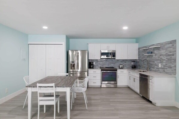 A modern kitchen with white cabinetry, stainless steel appliances, and a tiled backsplash.