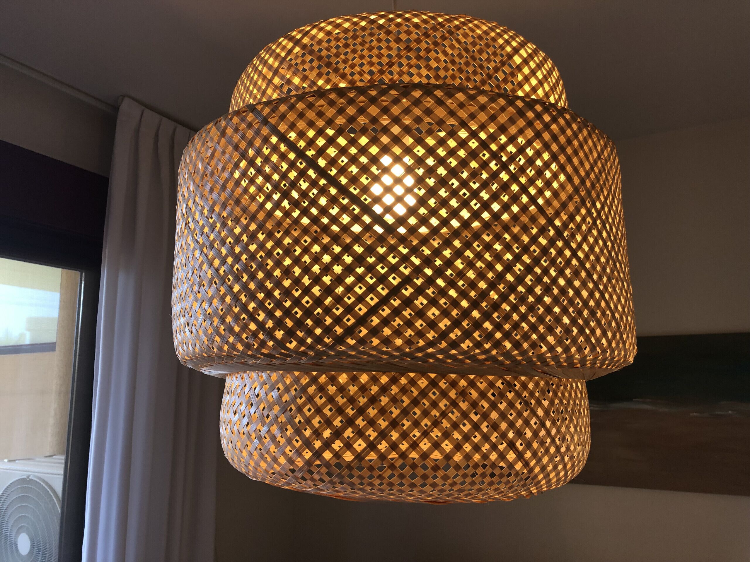 Een meerlaagse, geweven hanglamp met een warme gloed.